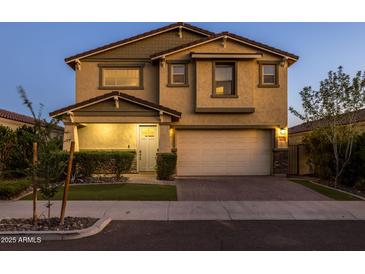 Two-story home features attached two car garage, stucco facade, and manicured front yard at dusk at 9911 E Telemetry Dr, Mesa, AZ 85212