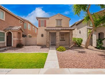 Charming two-story home featuring stone accents, a tiled roof, and a well-maintained, low-water landscape at 10 N 87Th Dr, Tolleson, AZ 85353