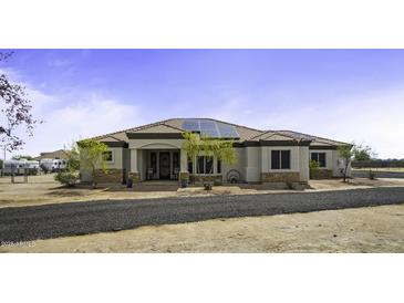 Single story home with desert landscaping, gravel drive, tile roof, solar panels and covered front porch at 2751 N Ralston Rd, Maricopa, AZ 85139