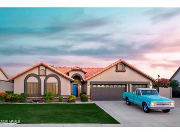 Charming single-story home with a blue door, lush lawn, mature plants and an attached two-car garage at 2917 E Northridge St, Mesa, AZ 85213