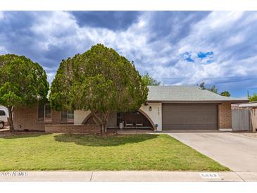 Charming single-story home with a well-manicured lawn and mature landscaping and attached two car garage at 6869 E Flossmoor Ave, Mesa, AZ 85208