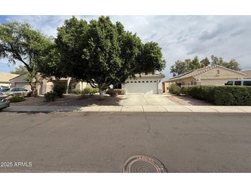 Charming single-story home featuring a lush, mature shade tree and a two-car garage at 7922 W Alex Ave, Peoria, AZ 85382
