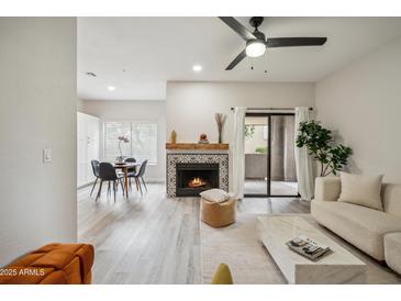 Bright living room featuring a decorative fireplace, modern furniture, and access to outdoor patio space at 9600 N 96 Th St # 130, Scottsdale, AZ 85258