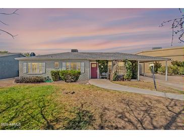 Charming single-story home with lush greenery, a brick facade, and a red front door under a colorful sky at 1712 E Montebello Ave, Phoenix, AZ 85016