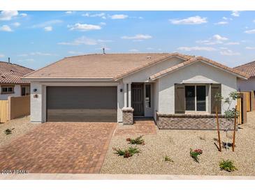 Charming single-story home featuring a brick driveway, two-car garage, and desert landscaping at 25616 N 148Th Dr, Surprise, AZ 85387