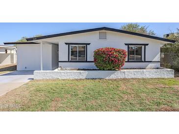 Charming home with fresh white paint, black trim, and a vibrant flowering bush at 340 W Riviera Dr, Tempe, AZ 85282