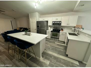 Bright, modern kitchen with stainless steel appliances, quartz counters, and breakfast bar seating at 6920 S 46Th Dr, Laveen, AZ 85339