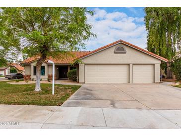 Charming single-story home with a well-manicured front yard, three-car garage, and terracotta roof tiles at 1333 E Bermuda Bay Ct, Gilbert, AZ 85234