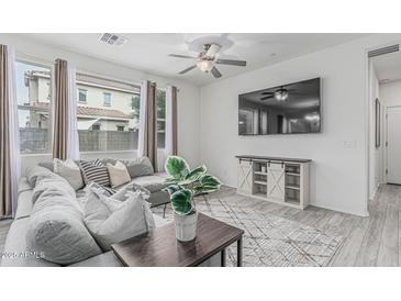 Bright living room with gray sectional, ceiling fan, stylish console and large windows offers cozy relaxation at 14870 W Encanto Blvd # 1061, Goodyear, AZ 85395