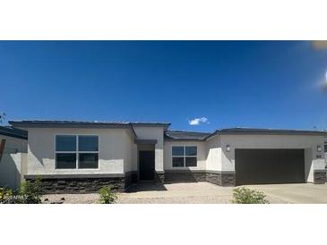 Contemporary single-story home featuring stucco siding, decorative stone accents, and a spacious two-car garage at 15386 W Cottontail Ln, Surprise, AZ 85387