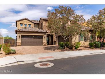 Charming two-story home with a three-car garage, beautiful brick driveway, and lush, flowering trees at 23126 N 45Th Pl, Phoenix, AZ 85050