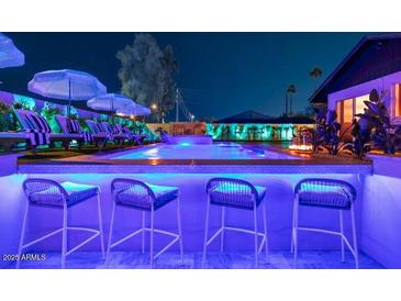 Inviting pool with barstool seating and lounge chairs offers a relaxing outdoor space for entertaining at 8734 E Amelia Ave, Scottsdale, AZ 85251