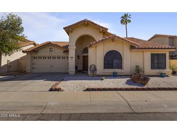 Charming single-story home featuring a red tile roof, arched entryway, and well-maintained landscaping at 10733 W Clover Way, Avondale, AZ 85392