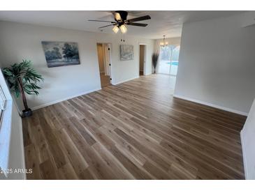 Bright living room with modern ceiling fan, wood-look flooring, and views to the backyard pool at 1545 W Marco Polo Rd, Phoenix, AZ 85027