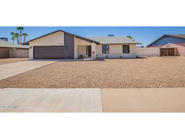Charming single-story home features a gravel yard, gray garage door, and modern architecture under a clear sky at 17040 N 39Th Ave, Glendale, AZ 85308
