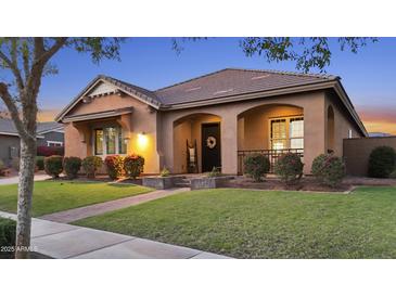 Charming home featuring a tile roof, covered porch, manicured lawn, and lovely shrubbery at 20546 W Summit Pl, Buckeye, AZ 85396