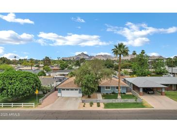 Charming single-Gathering home featuring a well-manicured lawn, mature trees, and a mountain backdrop under a bright blue sky at 3046 E Glenrosa Ave, Phoenix, AZ 85016