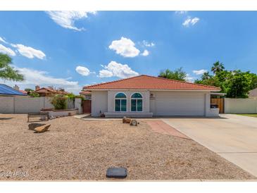 Charming single-story home featuring a red tile roof, arched windows, and a low-maintenance desert landscape at 4953 W Acoma Dr, Glendale, AZ 85306