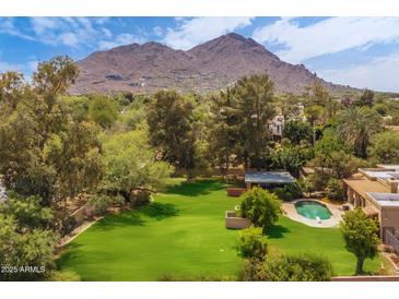 Expansive backyard with lush lawn, mature trees, and a sparkling pool, set against a scenic mountain backdrop at 6735 E San Juan Ave, Paradise Valley, AZ 85253