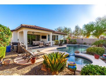 Beautiful backyard with pool, spa, covered patio, and lush landscaping, perfect for entertaining at 12798 W Dove Wing Way, Peoria, AZ 85383