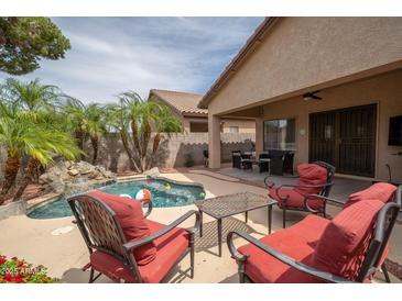 Inviting backyard pool with rock waterfall feature and covered patio seating area, perfect for outdoor entertaining at 12936 W Flower St, Avondale, AZ 85392