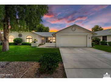 Charming single-story home featuring a two-car garage, well-maintained lawn, and desert landscaping under a vibrant sunset at 13023 W Tangelo Dr, Sun City West, AZ 85375