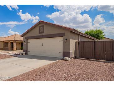 Single Gathering home featuring an attached garage with a two car driveway and low maintenance desert landscaping at 15633 W Acapulco Ln, Surprise, AZ 85379