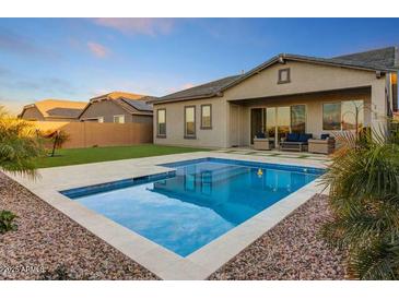 Inviting backyard pool and spa featuring lush landscaping and a covered patio, perfect for relaxation at 16566 W Saguaro Park Ln, Surprise, AZ 85387