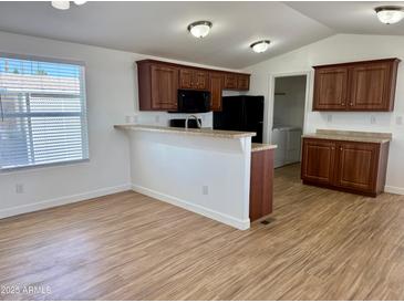 Bright eat-in kitchen with wood cabinets, black appliances, and wood-look floors at 7300 N 51St Ave # G102, Glendale, AZ 85301