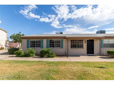 Charming single-story home featuring blue shutters and well-manicured landscaping at 849 N Revere -- # E, Mesa, AZ 85201