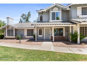 Charming two-story home featuring a well-maintained lawn, tiled roof, and inviting front porch at 860 N Mcqueen Rd # 1058, Chandler, AZ 85225
