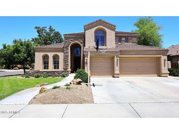 Inviting two-story home with a three-car garage, stone accents, and well-manicured front yard at 7272 W Crystal Rd, Glendale, AZ 85308