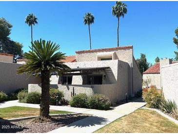 Inviting house featuring desert landscaping and palm trees against a clear blue sky at 7409 N Via Camello Del Norte -- # 138, Scottsdale, AZ 85258
