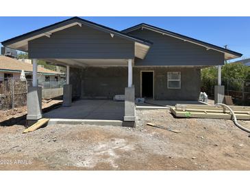 View of the exterior of a single story home with gray siding, a concrete patio, and a carport in progress at 1210 E Garfield St, Phoenix, AZ 85006