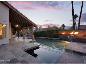Outdoor living space featuring a pool with fire bowls, covered patio, and lush landscaping for ultimate relaxation at 1940 E Citation Ln, Tempe, AZ 85284