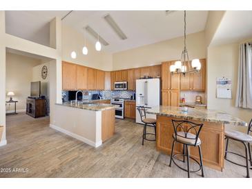 Bright kitchen features wood cabinets, granite counters, tile backsplash, island and pendant lighting at 992 S Roanoke St, Gilbert, AZ 85296
