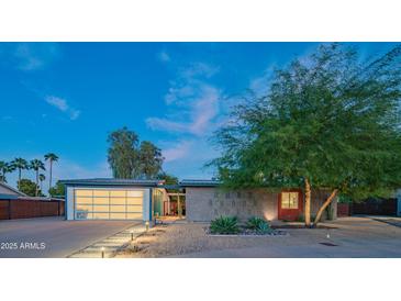Charming mid-century modern home with desert landscaping and a sleek, modern garage door at 10007 N 30Th Pl, Phoenix, AZ 85028