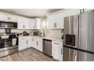 Well-lit kitchen featuring stainless steel appliances, white cabinets, and a stylish faucet at 11221 W Devonshire Ave, Phoenix, AZ 85037