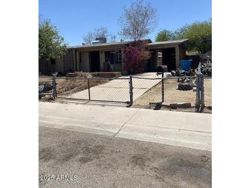 Modest single-story home with a gated yard and mature flowering shrub in need of some TLC at 1747 W Maldonado Rd, Phoenix, AZ 85041