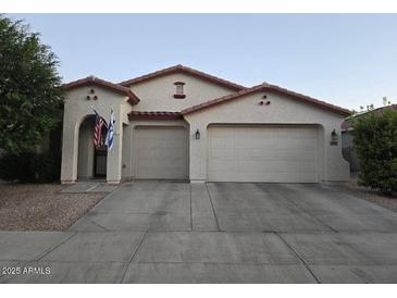 Charming single-story home featuring a two-car garage, landscaped yard, and a welcoming entrance with flags at 17825 W Lincoln St, Goodyear, AZ 85338