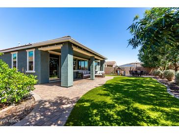 Inviting covered patio with stylish seating overlooks the lush green lawn and landscaped backyard at 23179 S 225Th Pl, Queen Creek, AZ 85142