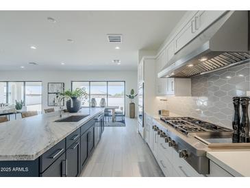 Bright open kitchen with white cabinets, stainless steel appliances, and an island with marble countertop at 24000 S 218Th Pl, Queen Creek, AZ 85142