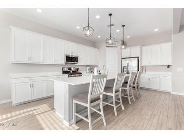 Modern kitchen with white cabinetry, a center island with seating, and stainless steel appliances at 32582 N Durango Ln, San Tan Valley, AZ 85143