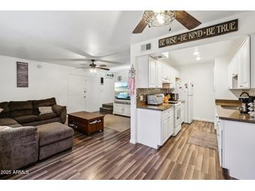 Inviting living room and kitchen featuring stylish laminate flooring, ceiling fan, and well-equipped white kitchen at 5923 W Townley Ave, Glendale, AZ 85302