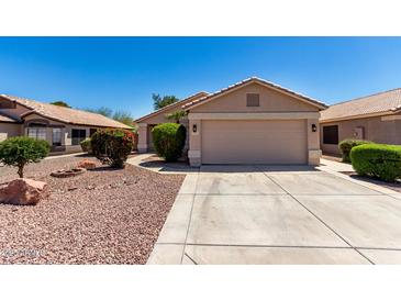 Charming single-story home with well-maintained landscaping and a two-car garage at 13439 W Desert Ln, Surprise, AZ 85374