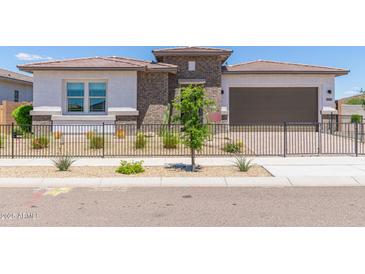 Charming single-story home featuring low-maintenance desert landscaping and a sleek black fence at 14116 W Honeysuckle Dr, Surprise, AZ 85387