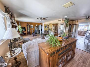 Open concept living room showcasing a fireplace, wood-look floors, and a ceiling fan at 4621 E Desert Forest Trl, Cave Creek, AZ 85331