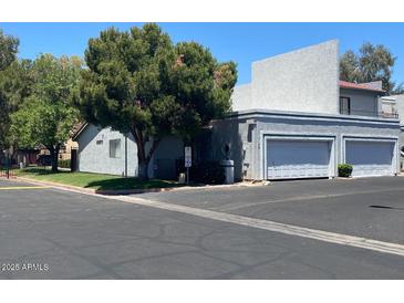 Exterior shot of a home featuring a two-car garage and mature trees at 8702 N Shadow Ln, Peoria, AZ 85345