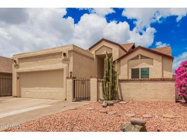 Charming desert home featuring low-maintenance landscaping, attached garage, and gated front entryway at 10244 N 65Th Ln, Glendale, AZ 85302