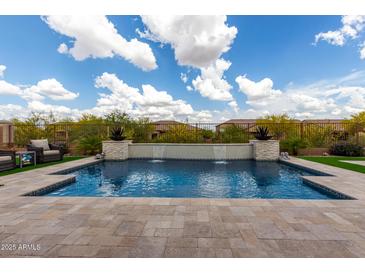Inviting pool area with artificial turf, a soothing waterfall feature, and comfortable patio furniture at 24035 N 171St Dr, Surprise, AZ 85387